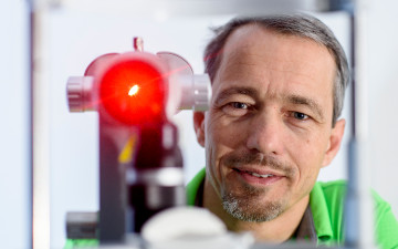 Dr. Andreas Müller neben dem Laser, mit dem er Glaukom / Grüner Star behandelt