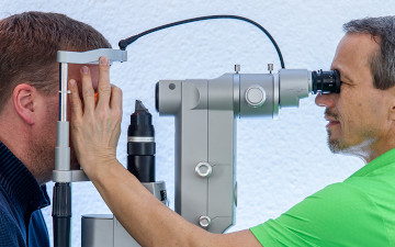 Augenarzt Dr. Andreas Müller führt bei einem männlichen Patienten die routinemäßige Augen-Vorsorge durch