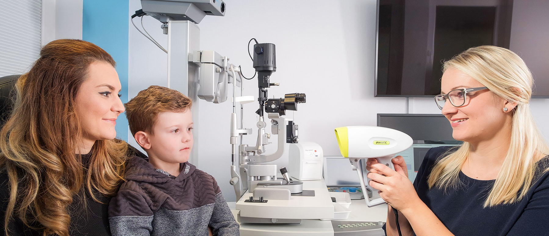 Die Orthoptistin behandelt bei den Augenpartnern Walsrode ein Kind, das von seiner Mutter gehalten wird