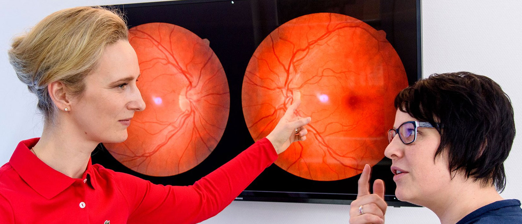 Dr. med. Sina Ahlers bespricht mit einer Patientin das auf dem großen Monitor sichtbare Untersuchungsergebnis ihrer Augen 